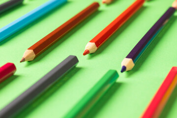 Composition of colorful crayons on green surface