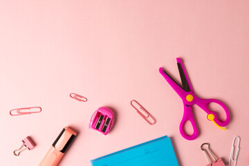 Composition of pink and red school equipment on pale pink surface with copy space