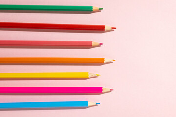 Composition of colorful crayons on pale pink surface with copy space