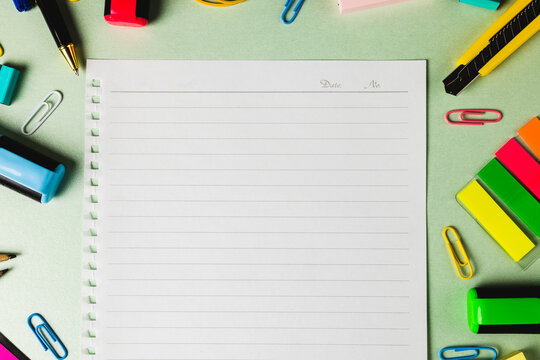 Composition of notebook with copy space and frame of school tools on green surface