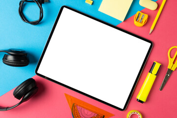 Composition of tablet with copy space and school equipment on blue and pink surface