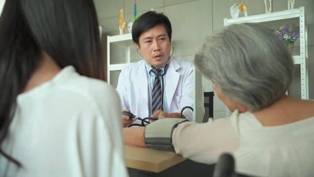 Male doctor measures the blood pressure of a senior female patient in the examination room.