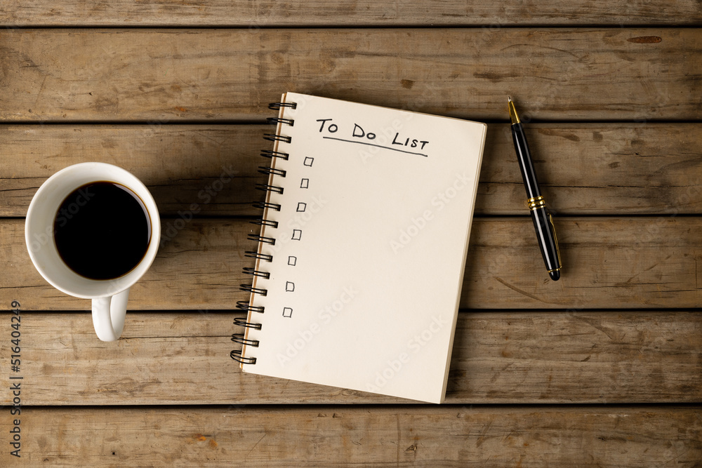 Poster image of notebook with to do list and copy space on wooden surface with coffee and pen