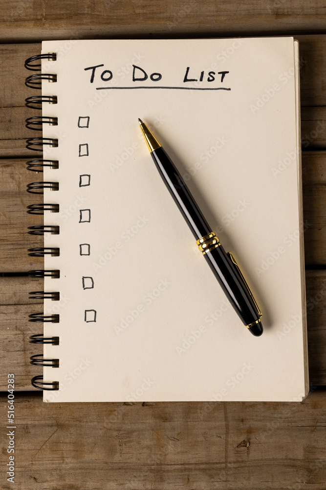 Poster vertical image of notebook with to do list and copy space on wooden surface with pen