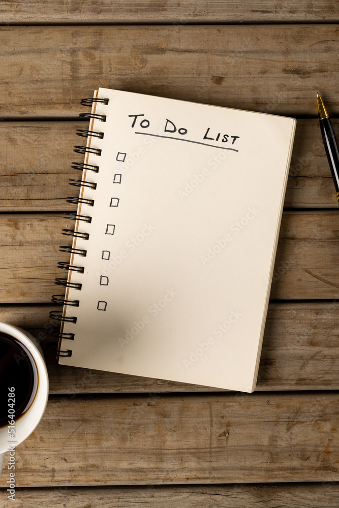 Poster vertical image of notebook with to do list and copy space on wooden surface with coffee and pen