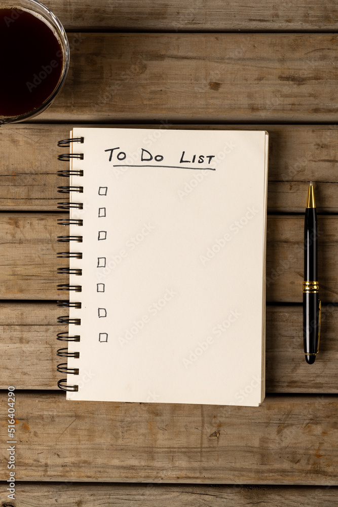 Poster vertical image of notebook with to do list and copy space on wooden surface with coffee and pen