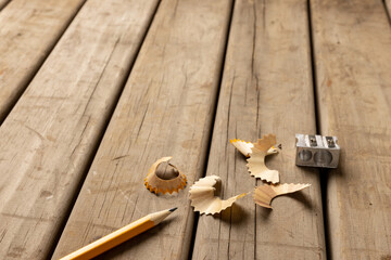 Image of pencil, sharpener and peelings on wooden background