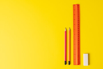 Composition of rulers, pencils and eraser on yellow surface with copy space