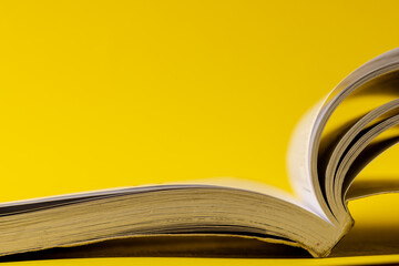 Image of open book on yellow surface with copy space