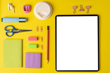 Composition of school equipment and tablet with copy space on yellow surface