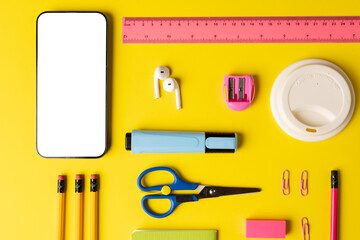 Composition of school equipment and smartphone with copy space on yellow surface