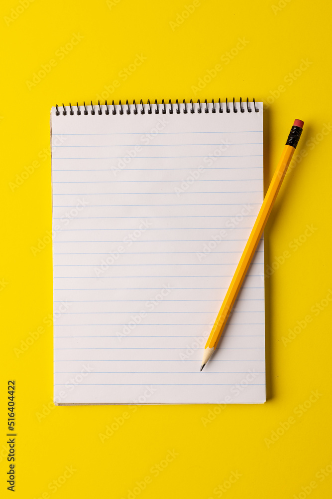 Poster vertical image of notebook with copy space and pencil on yellow surface