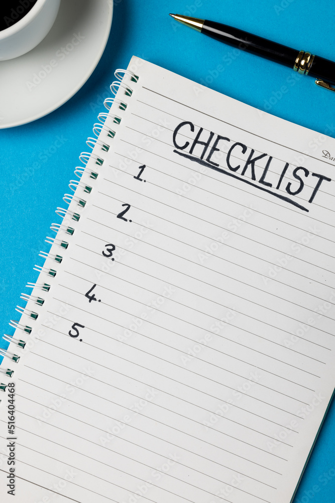 Poster vertical image of notebook with checklist and copy space, coffee and pen on blue surface