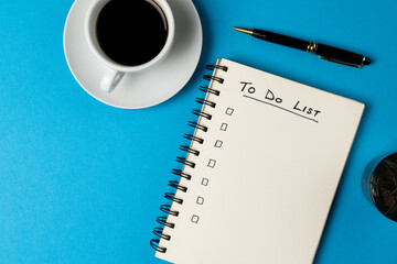 Image of notebook with to do list and copy space, coffee and pen on blue surface
