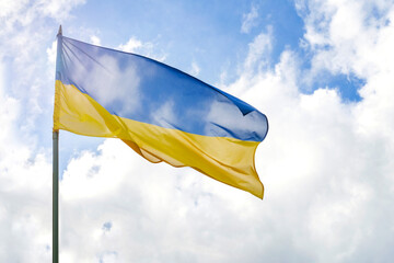 Flag of Ukraine in front of cloudy and sunny blue sky