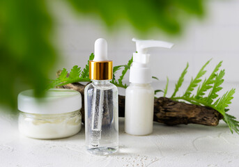 Cosmetics for face care on a bright table. Hand cream and a green twig in the background. Light background