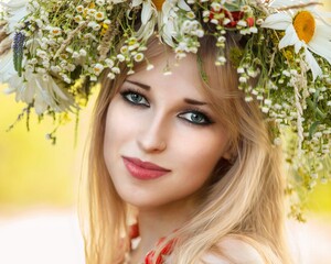 Beautiful girl with green eyes on her head a wreath of wild flowers