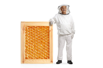 Mature male bee keeper in a uniform leaning on a honeycomb frame