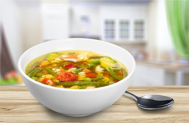 Tasty clear soup with beef slices and vegetables. Served in bowl on desk