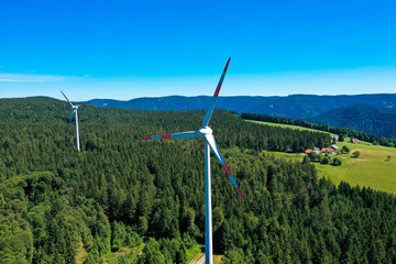 Aerial view of wind power plant in the bright green meadow and fir trees. St. Peter, Black forest,...
