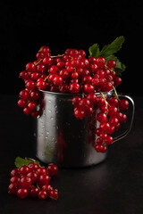 Blurred image of a red currant in a metal cup on a black background.