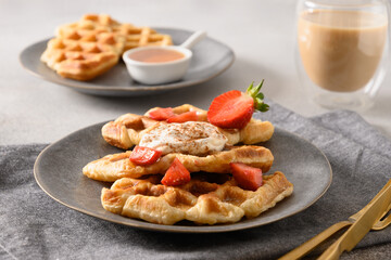 Trendy breakfast with croffles and morning coffee, strawberries. Croissant as waffle. Close up.