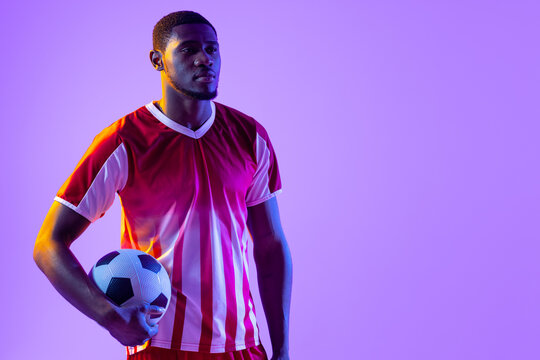 African american male soccer player with football over neon pink lighting