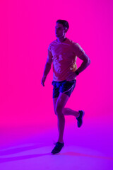 Fototapeta na wymiar Caucasian male tennis player running over neon pink lighting