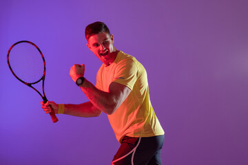 Happy caucasian male tennis player with tennis racket over neon pink lighting