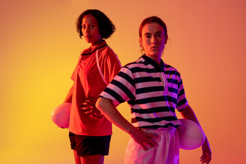 Portrait of diverse female rugby players with rugby balls over neon pink lighting