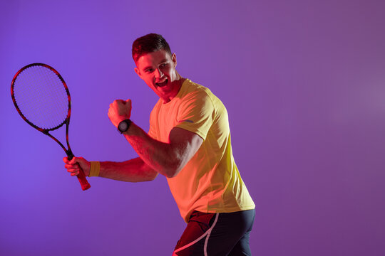 Happy Caucasian Male Tennis Player With Tennis Racket Over Neon Pink Lighting