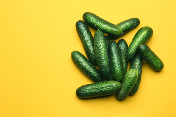 Heap of fresh ripe cucumbers on yellow background, flat lay. Space for text