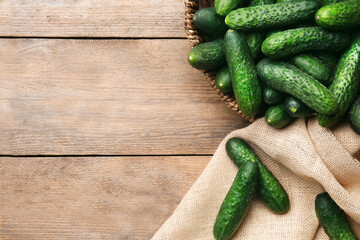 Fresh ripe cucumbers on wooden background, flat lay. Space for text