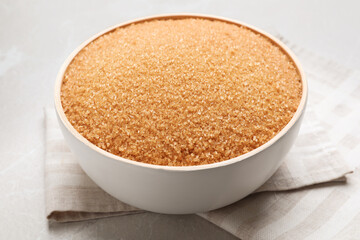 Brown sugar in bowl on light grey table, closeup