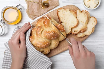 Rollo Brot Woman cutting homemade braided bread at white wooden table, top view. Traditional Shabbat challah  © New Africa