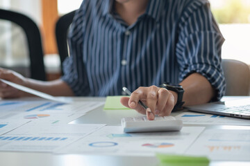 Business men use calculators and graph analysis laptops to plan marketing strategies and make profitable investments in the company.