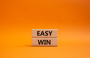 Easy win symbol. Wooden blocks with words 'Easy win'. Beautiful orange background. Business and...
