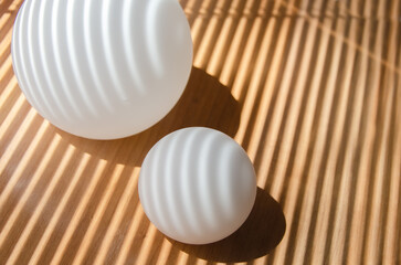 Straight and curved shadows on spherical surface of white ball and plane. abstract composition. white frosted glass balls with streaks of light and shadow from window with blinds. selective focus