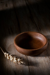 Brown wooden cup and ear of wheat on a wooden table