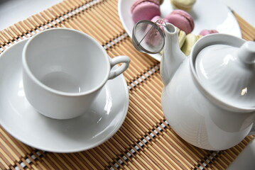Fototapeta na wymiar Porcelain teapot with a cup of tea and macaroons