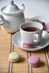 Obraz na płótnie Canvas Porcelain teapot with a cup of tea and macaroons