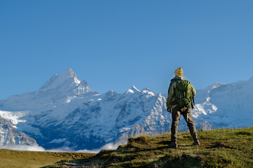 Tourist with a backpack in the rocky mountains. Mountain hiking and active tourism. Grindewald, Switzerland.
