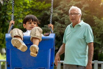 Grandfather and grandson on a swing in the park. Generations concept. Family concept