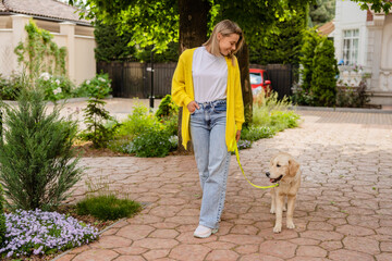 happy smiling woman in yellow sweater walking at her house with a dog golden retriever