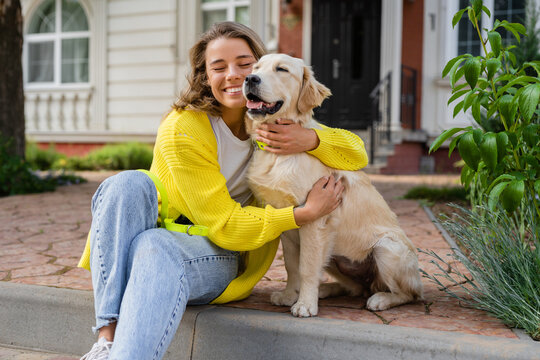 happy smiling woman in yellow sweater walking at her house with a dog golden retriever