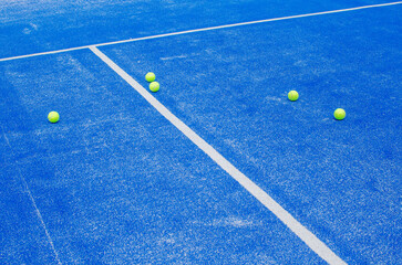 selective focus, several paddle tennis balls on a blue artificial grass paddle tennis court
