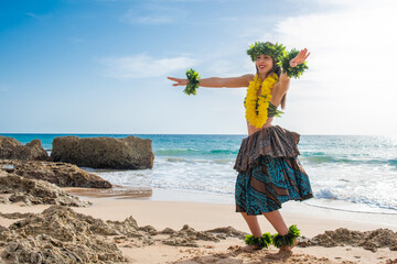 Hula dancer dancing Hawaiian dance on the beach in tropical outfit. Smiling woman dancing a hawaii...