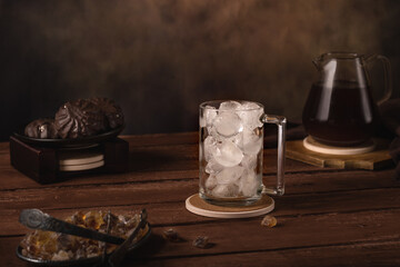 Glass with ice. Nearby is a coffee pot, a jug of cream, marshmallows, and caramelized sugar. Cold refreshing coffee summer drink.