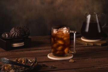 Iced coffee in a glass. Nearby are a coffee pot, marshmallows and caramelized sugar. Cold refreshment coffee summer drink.