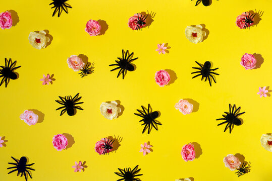 Colorful flowers with creepy, scary, black spiders on yellow background. Horror Halloween decor.